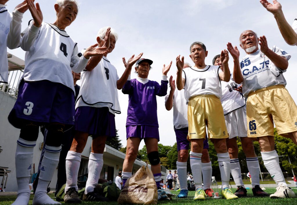 White Bear’s goalkeeper Shingo Shiozawa (center), 93, claps with his teammates following the Japanese custom 'temije' (a ceremonial rhythmic hand clapping)